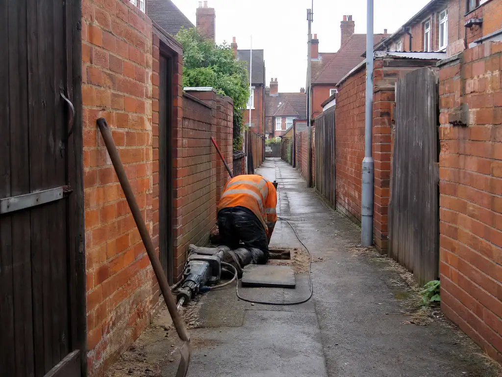 Alley behind a row of terraced houses where a shared water supply pipe runs, Nottingham