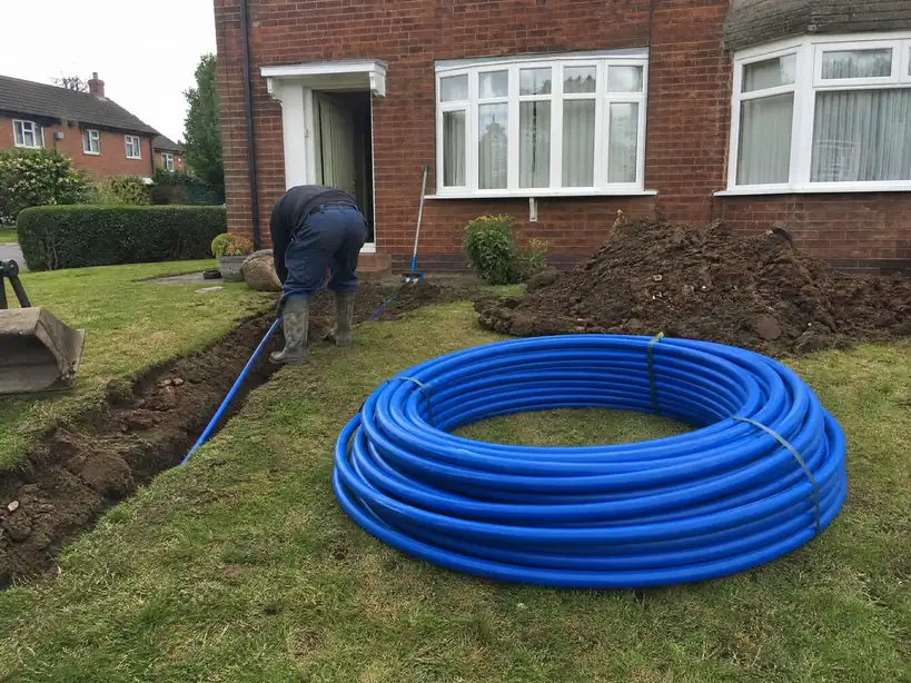 Coil of new blue MDPE water supply pipe ready to lay in a front garden, Nottingham