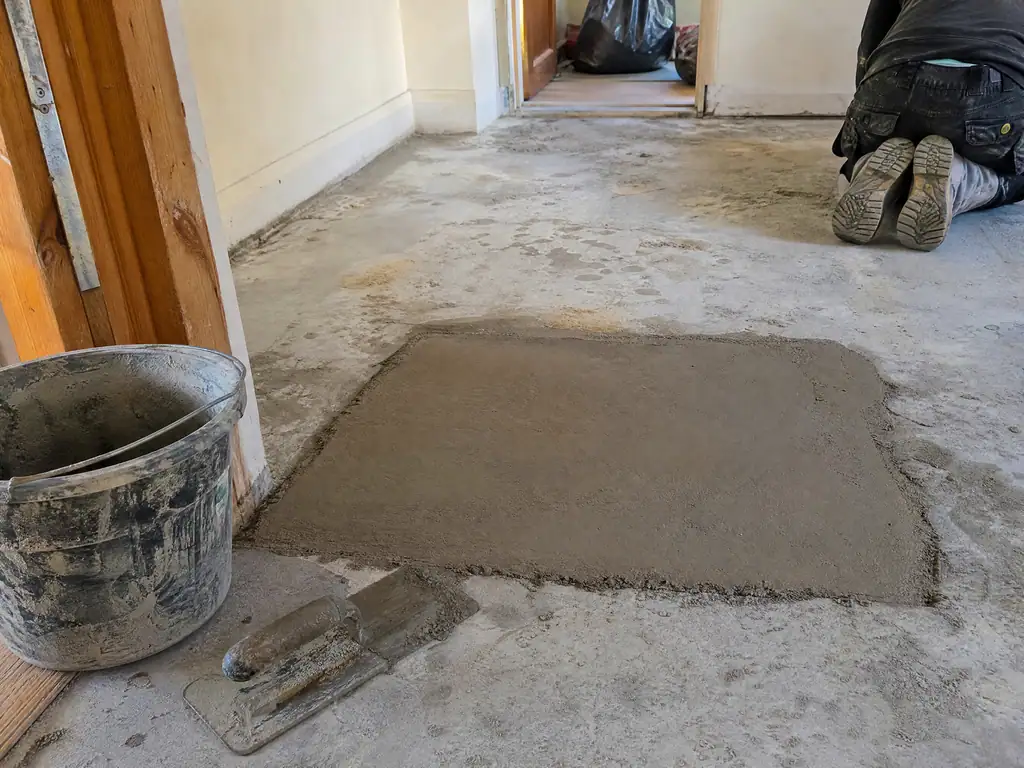 New screed patch drying after a leak under a concrete floor was repaired, Nottingham
